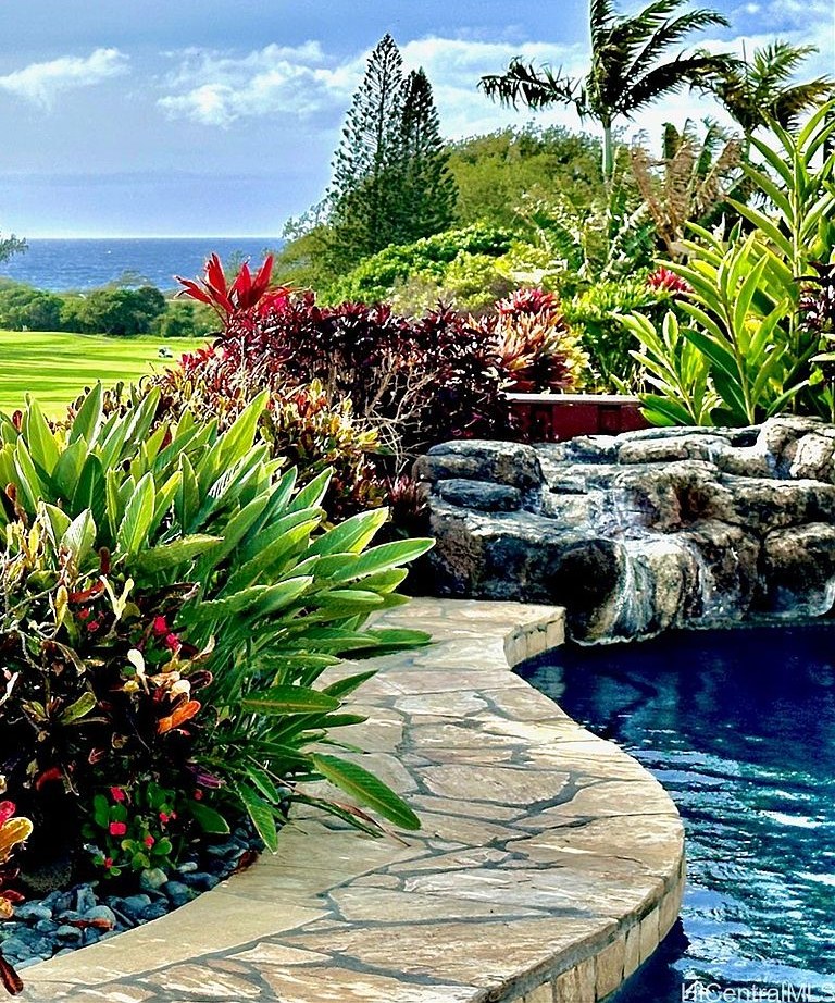Lava-rock pool feature with tropical plantings and ocean horizon beyond
